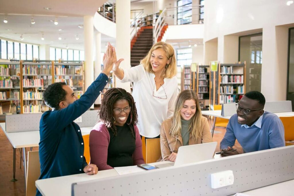 Strive Not to Be a Success, Cheerful multiethnic students having high five with teacher