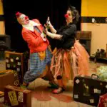 Meaning of Acting and Actor: Clowns performing indoors with vibrant costumes and stage props, capturing joyful fun.