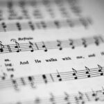 Putting Lines and Text to Music: Close-up of black and white sheet music featuring musical notes and lyrics in focus.