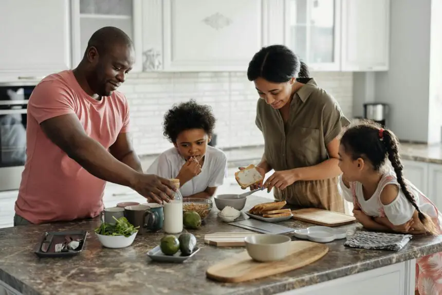 function of each family member: A joyful family enjoys preparing a healthy meal together in their modern kitchen.