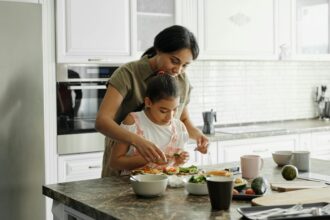 Roles Of The Mother In The Family: A mom and daughter share a bonding moment while preparing a healthy lunch together in the kitchen.