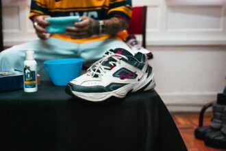 Guidelines For Care Of Personal Belongings : Close-up of Nike sneaker with cleaning supplies on a black table indoors.