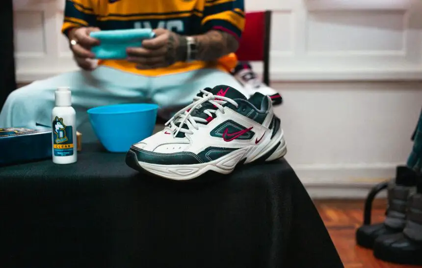 Guidelines For Care Of Personal Belongings : Close-up of Nike sneaker with cleaning supplies on a black table indoors.