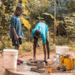 Personal and Family Resources: Two children collecting water from a well in a forest setting, featuring vibrant nature.