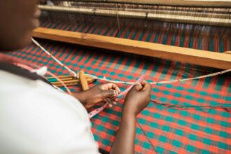 introduction to weaving: person in white pants lying on red and white hammock